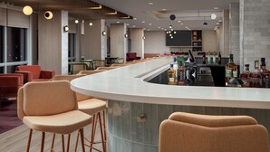 A modern bar area with a curved counter, bar stools, and a variety of liquor bottles. - TRU by Hilton Miami Airport South Blue Lagoon, FL (Miami)