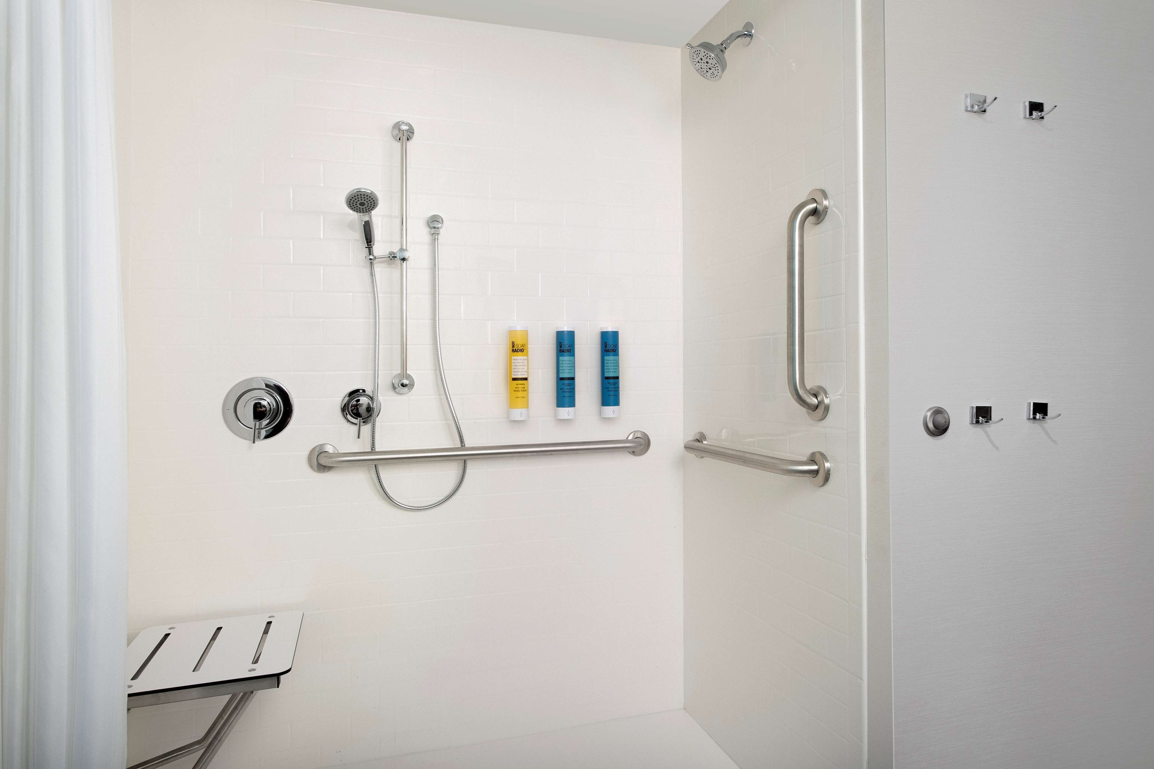 Un baño moderno con ducha, barras de apoyo y artículos de aseo.