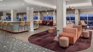 A spacious lobby with a bar area, seating arrangements, and large windows offering city views. - TRU by Hilton Miami Airport South Blue Lagoon, FL (Miami)