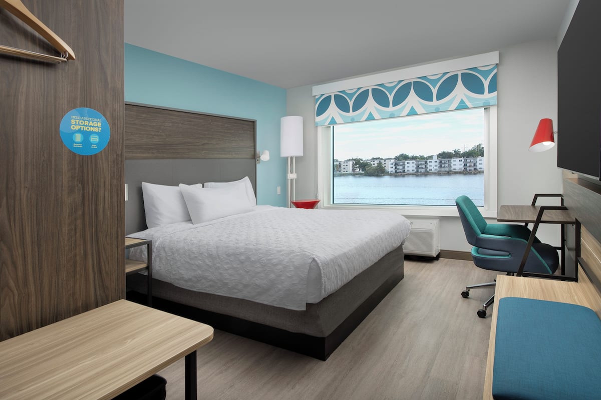 Una habitación de hotel moderna con cama, escritorio, silla y vista a un cuerpo de agua.