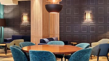 Un espace repas moderne avec une table ronde en bois, entourée de chaises recouvertes d’un tissu de couleur turquoise.