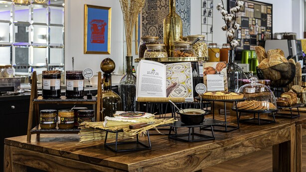 A bakery display with various baked goods, jars of preserves, and a menu board.
