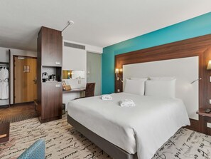 A hotel room with a large bed, a desk with a chair, a wardrobe, and a bathroom visible through an open door. - Mercure Paris Porte d'Orléans (Montrouge)
