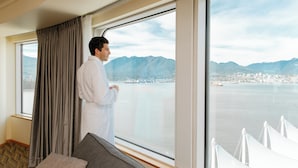 Una habitación con un ventanal grande, un sofá y una persona de pie junto a la ventana.