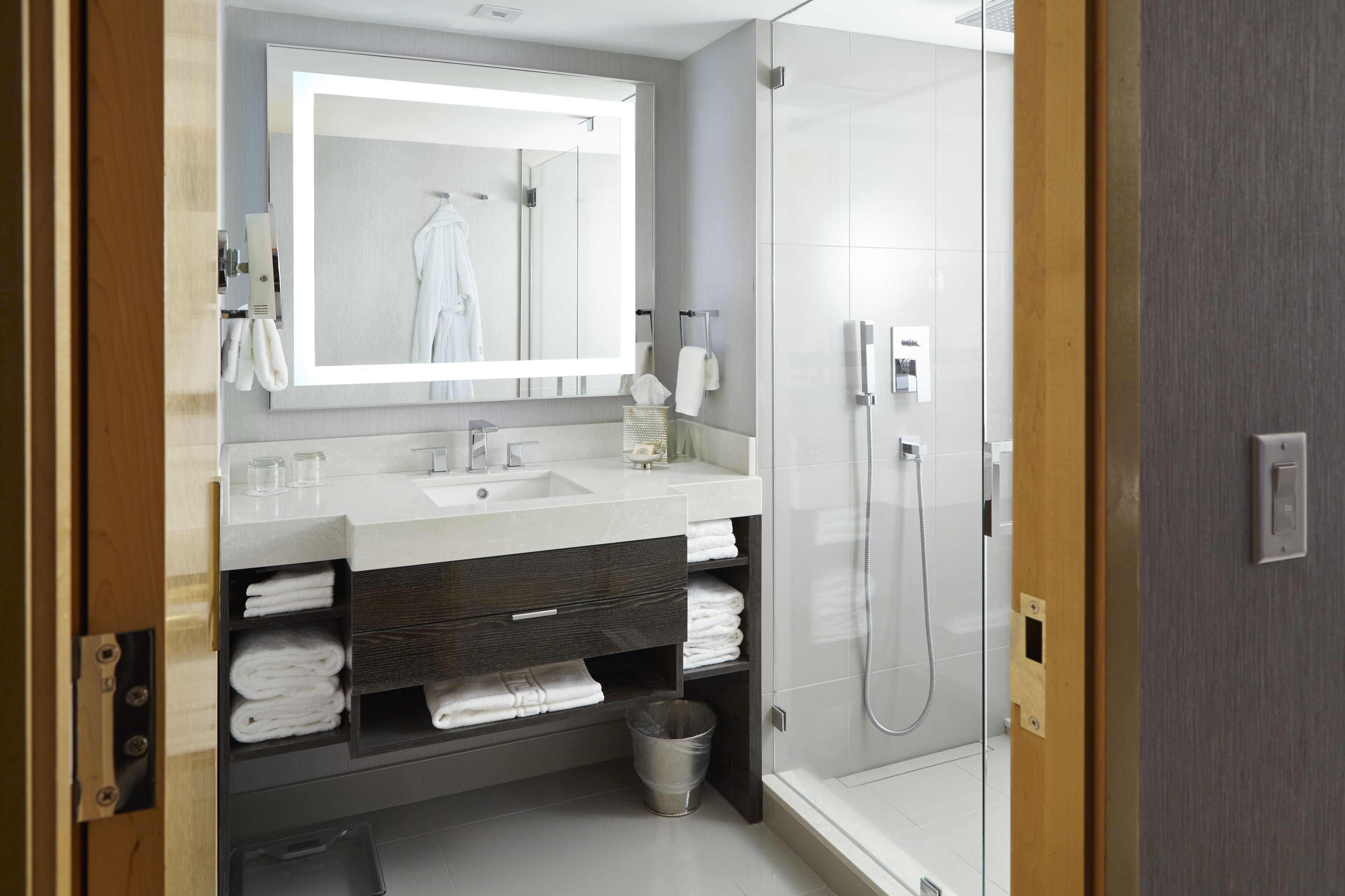 Une salle de bain moderne avec un grand miroir, un lavabo et une douche.