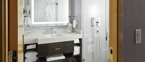 A modern bathroom with a large mirror, a sink, and a shower.
