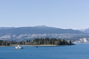 Un lago con un bote, una isla boscosa y una cadena montañosa al fondo.