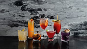 Une sélection de six cocktails présentés sur une surface réfléchissante, avec un fond en marbre.