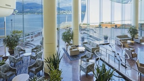 A modern hotel lobby with a view of a body of water and a cityscape. - Pan Pacific Vancouver (Vancouver)