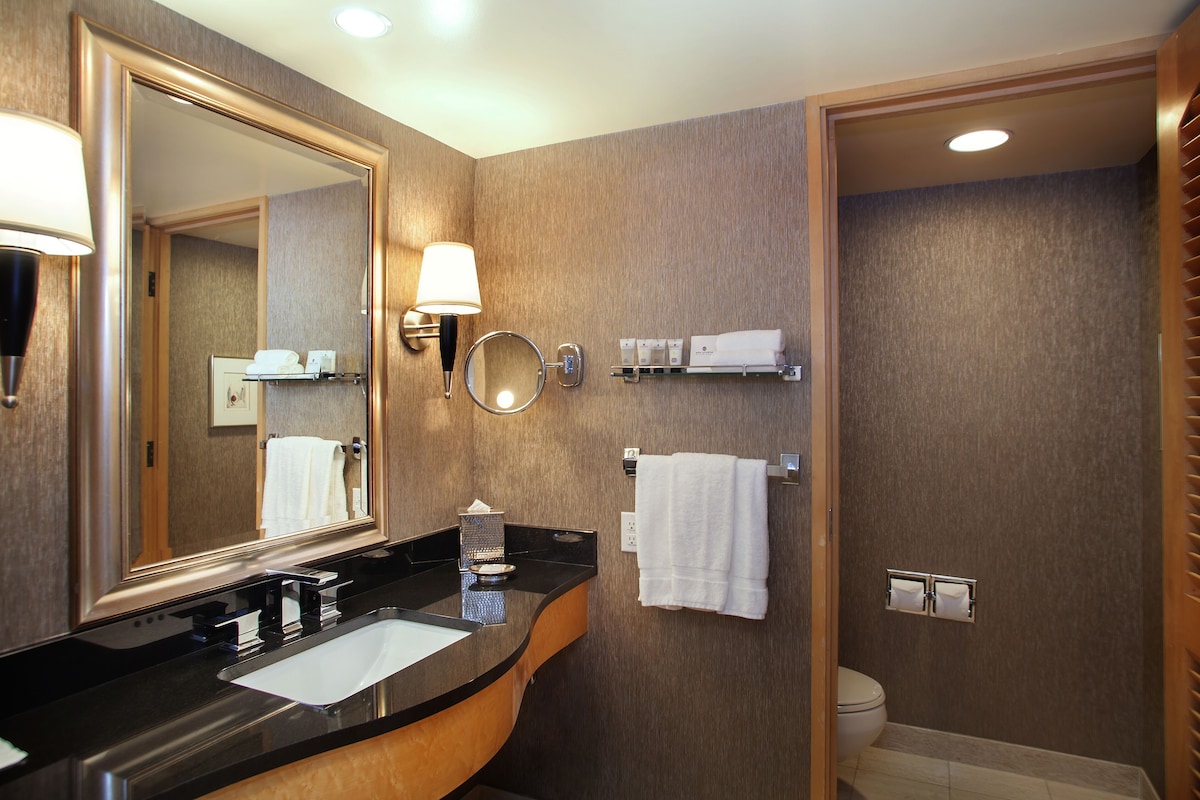 A modern bathroom with a large mirror, a sink, a toilet, and a shower area.