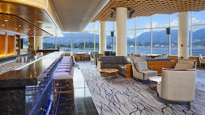 A modern hotel lobby with a bar, seating area, and large windows offering a mountain view. - Pan Pacific Vancouver (Vancouver)