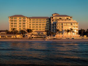 A multi-story hotel with balconies, located near a beach with palm trees. - Naples Beach Club, A Four Seasons Resort (Naples)