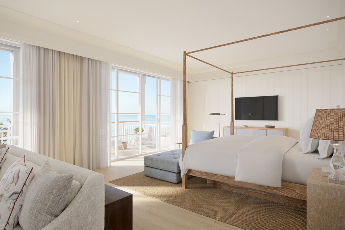 A modern hotel room with a large bed, a balcony with a view, a TV, and a sofa.