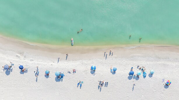 A beach with clear turquoise water, white sand, and people enjoying the sun and sea. - Naples Beach Club, A Four Seasons Resort (Naples)