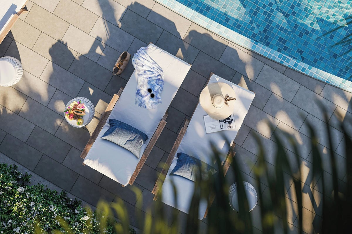 Luftaufnahme eines Poolbereichs mit Fliesenboden, Liegestühlen und einem Tisch mit einer Fruchtschale.