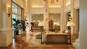 A spacious lobby with a high ceiling, large windows, and a central seating area with a sofa and lamps. - Naples Beach Club, A Four Seasons Resort (Naples)