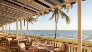 An outdoor dining area with tables and chairs, overlooking the ocean. - Naples Beach Club, A Four Seasons Resort (Naples)