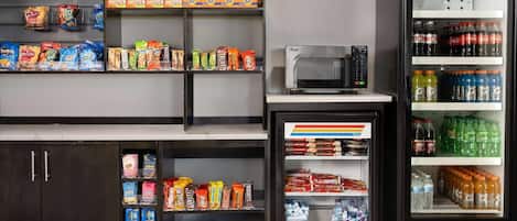 A vending machine with various snacks and drinks, a microwave, and a refrigerator stocked with beverages.