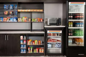 A vending machine with various snacks and drinks, a microwave, and a refrigerator stocked with beverages.