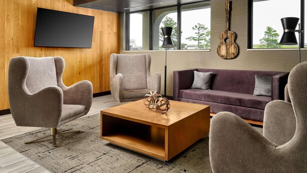 A modern living room with a flat-screen TV, a wooden coffee table, and a sofa. - Radisson Hotel West Memphis (West Memphis)