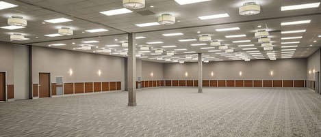 A spacious conference room with a patterned carpet, ceiling lights, and wooden paneling along the walls.