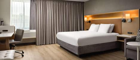 Une chambre d’hôtel équipée d’un lit, d’un bureau, d’une chaise et offrant une vue sur l’extérieur.