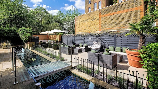 A courtyard with a pool, outdoor seating, and a brick wall. - Holiday Inn London - Kensington High St. by IHG (London)