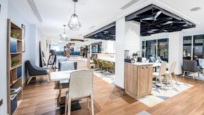 A modern interior with a reception desk, seating area, and a kitchen counter. - Holiday Inn London - Kensington High St. by IHG (London)