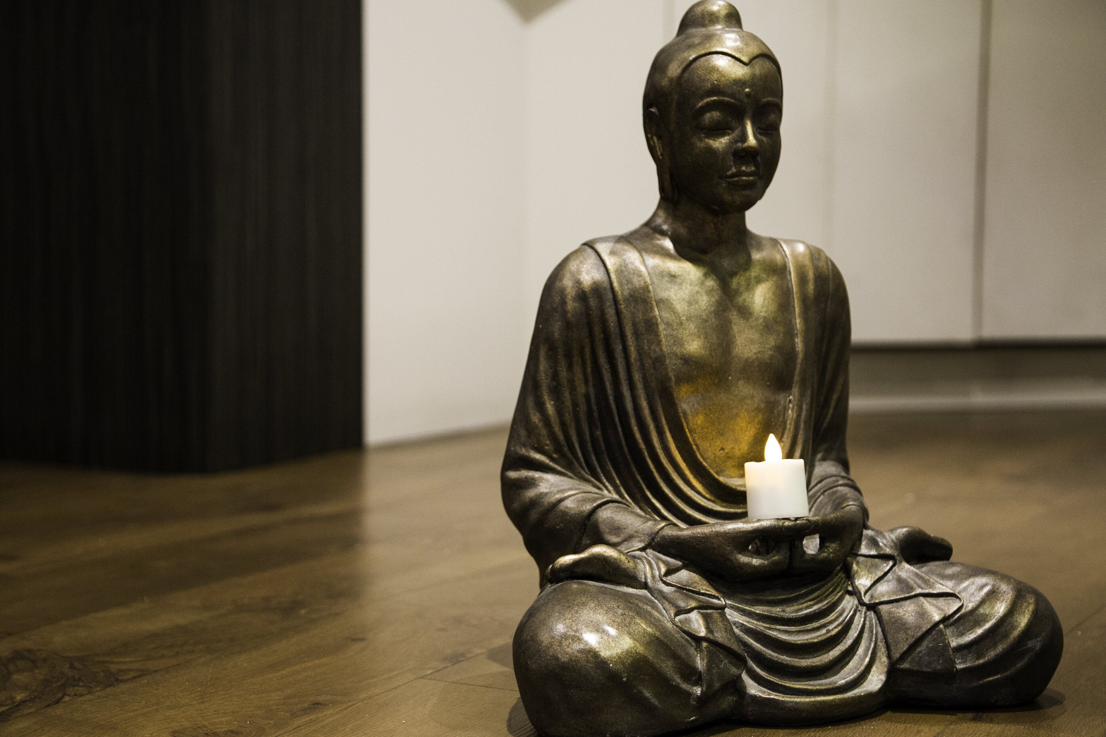 A bronze statue of a seated figure holding a candle.