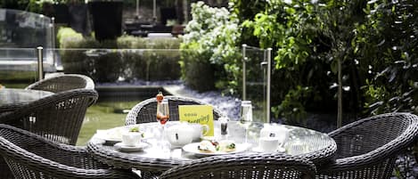 A table set for breakfast with wicker chairs, a glass table, and a 'Good Morning' sign.