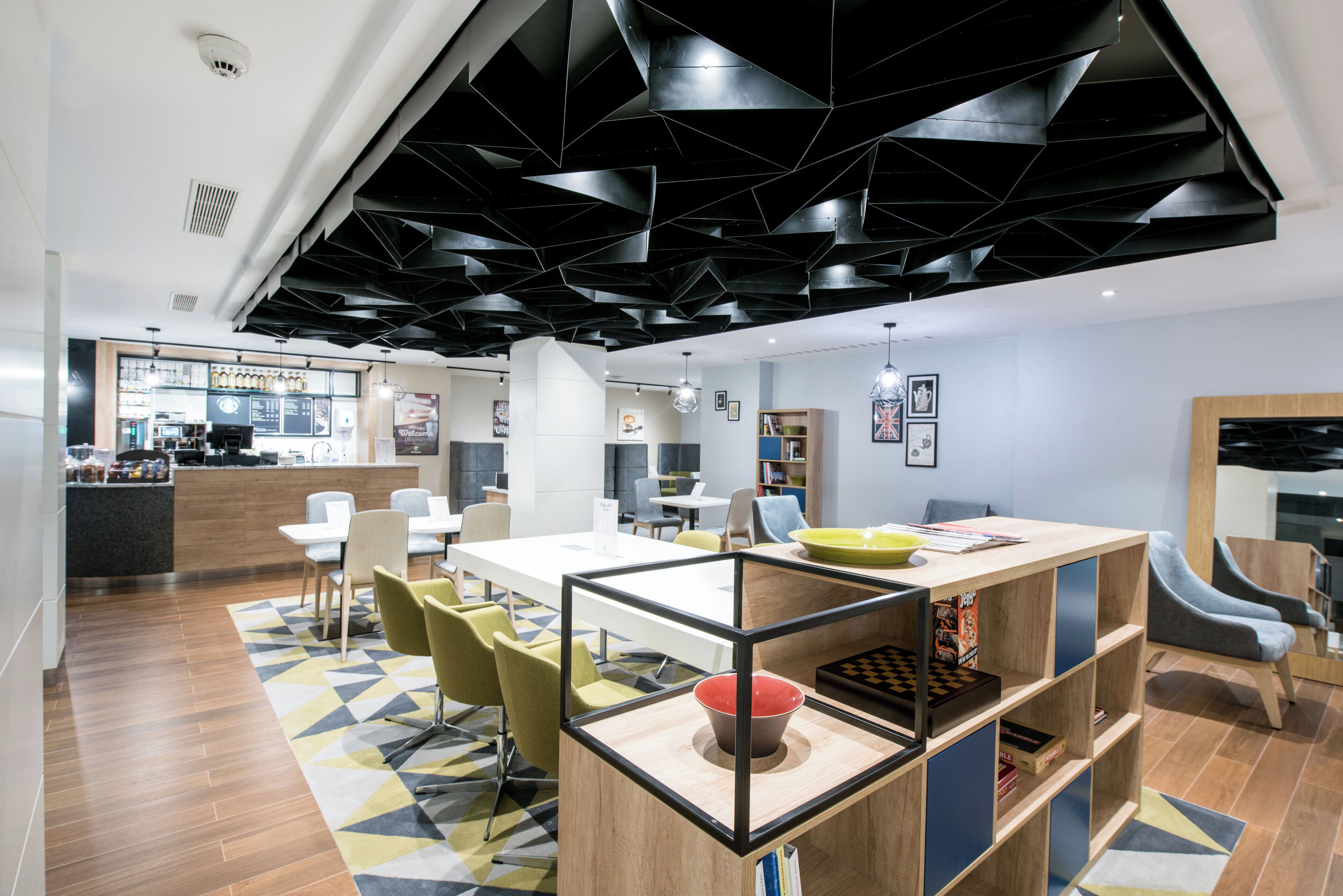 Ein modernes Interieur mit einer zentralen Essecke, einer Bar und einer Sitzecke mit einem geometrisch gemusterten Teppich.