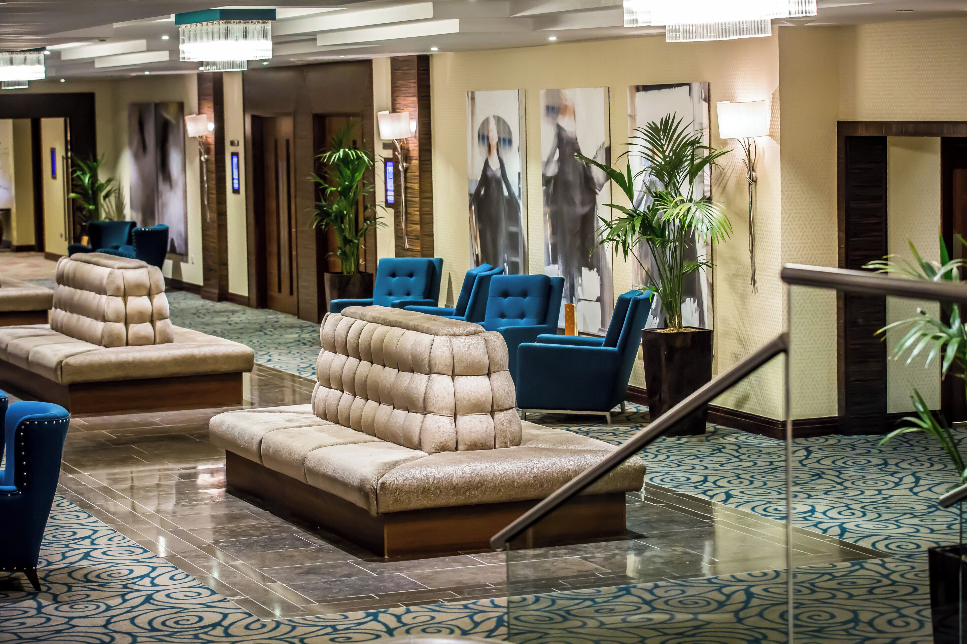 A hotel lobby with seating areas, a staircase, and a patterned floor.