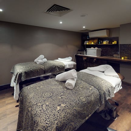 A room with two beds, a massage chair, and a small kitchenette.