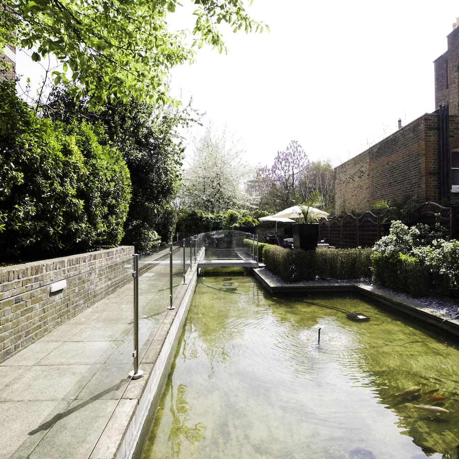 A narrow water feature with a brick wall on one side and a building on the other.