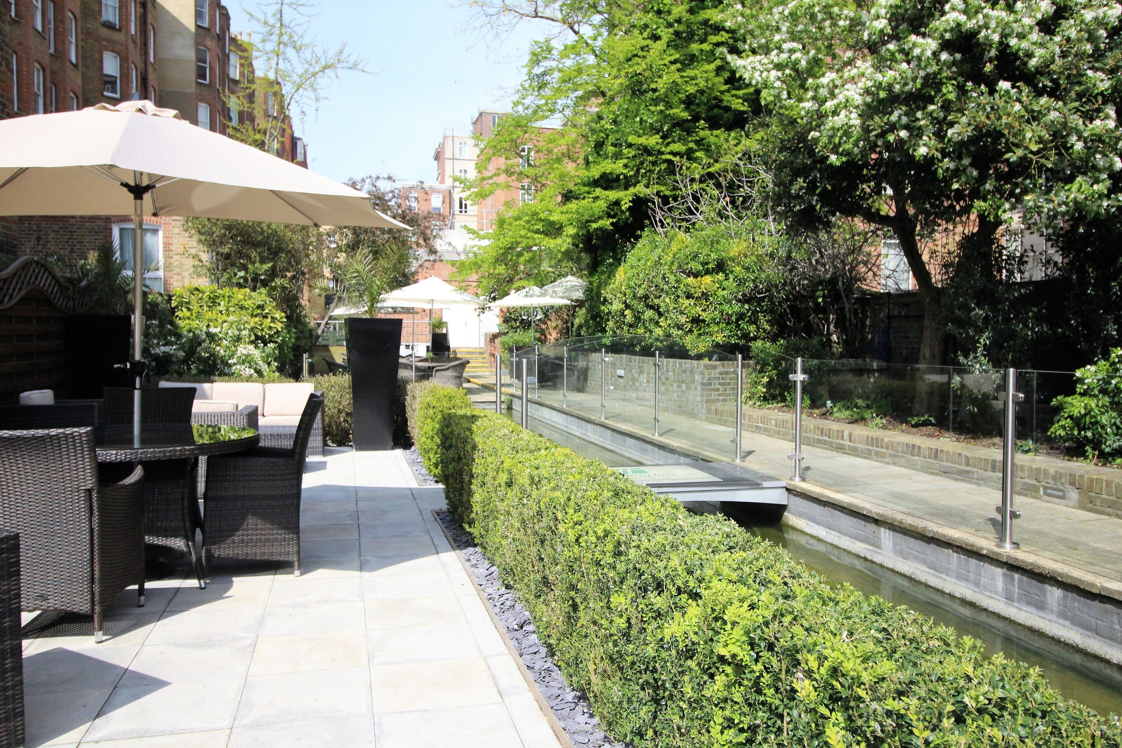 An outdoor patio area with wicker furniture, a table, and an umbrella.
