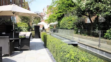 An outdoor patio area with wicker furniture, a table, and an umbrella.