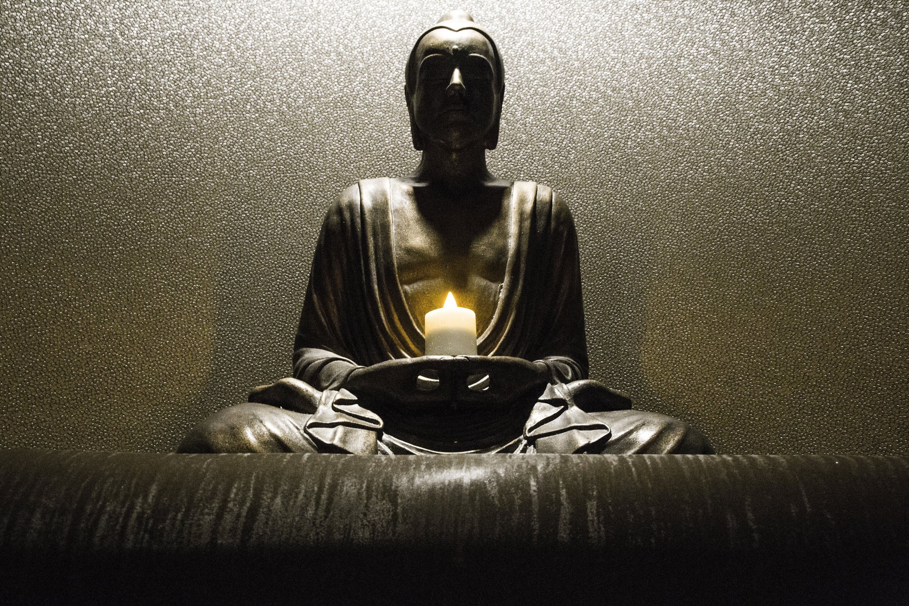 A statue with a candle in front of it.