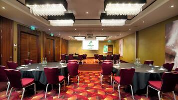 A conference room with round tables, red chairs, and a carpeted floor.