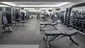 A gym with various exercise equipment, including benches, dumbbells, and weight machines.