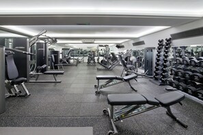 Una palestra con diverse attrezzature per esercizi, tra cui panche, manubri e macchinari per pesi.