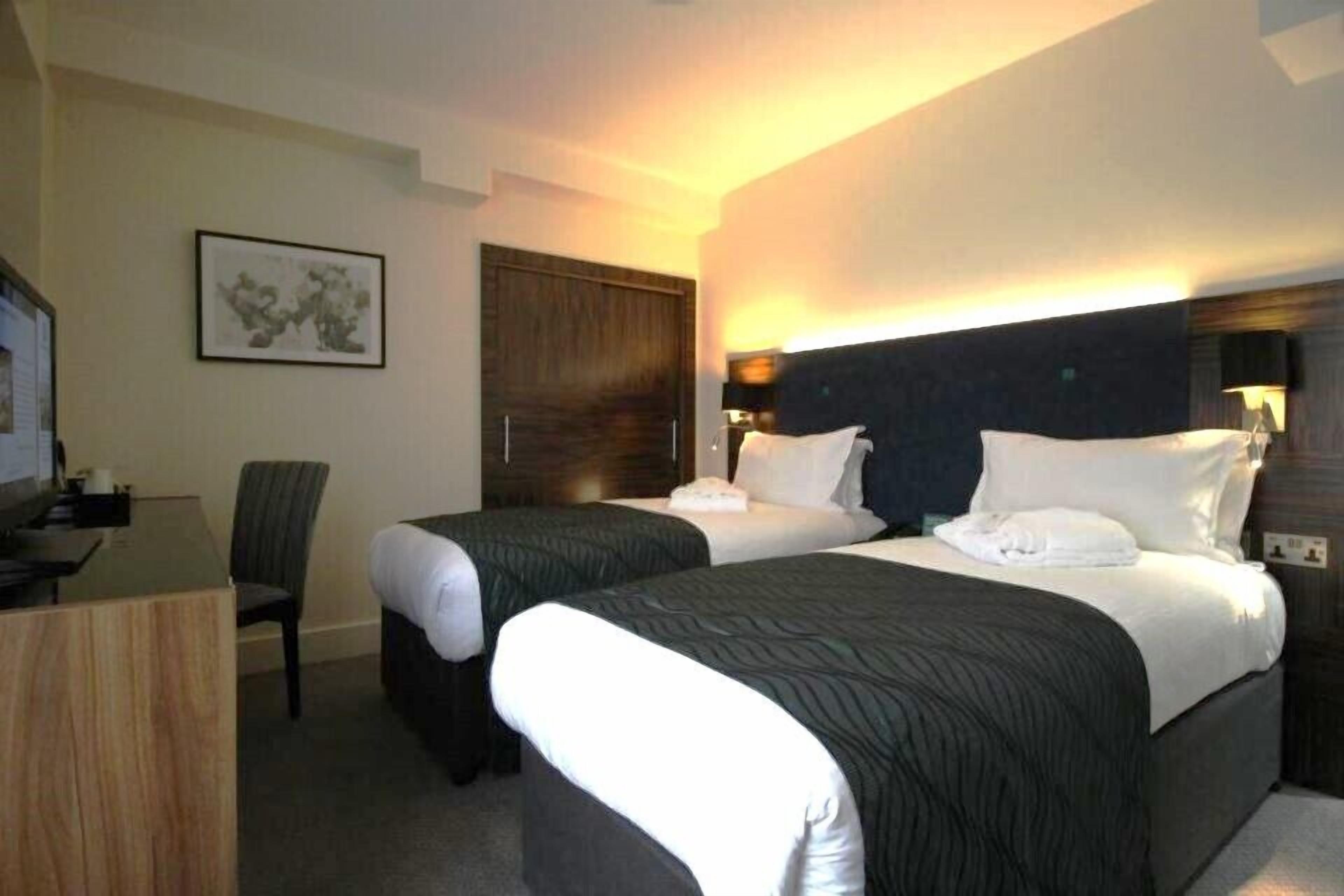 A hotel room with two beds, a desk, and a chair.