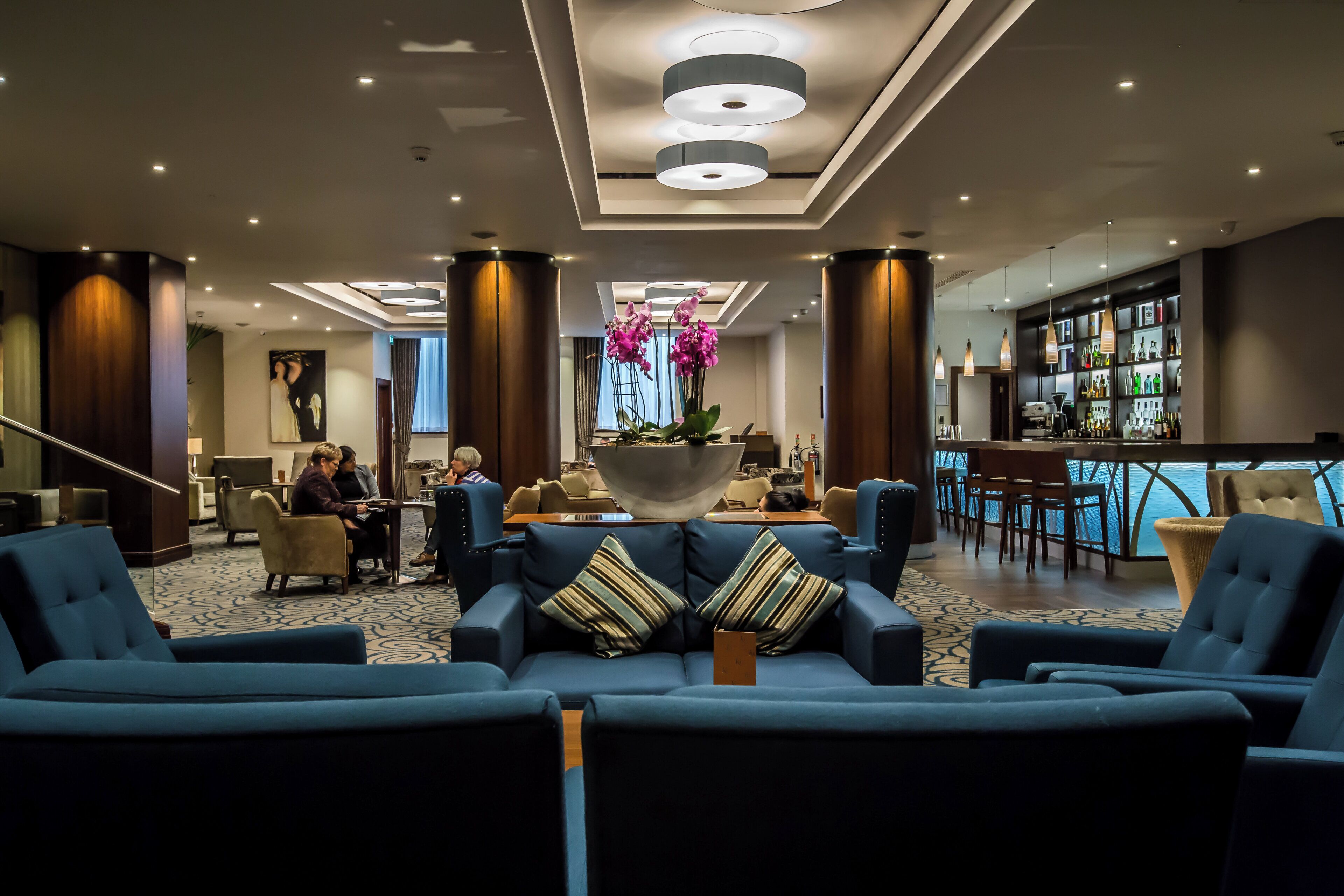 Una hall d'albergo con un bar, un'area salotto e la reception.