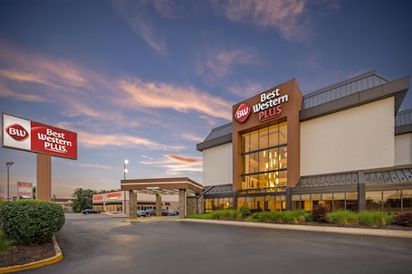 A Best Western Plus hotel with a large sign, a covered parking area, and a clear sky.