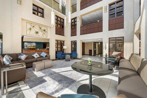 A spacious lobby with a high ceiling, multiple seating areas, and a central round table.