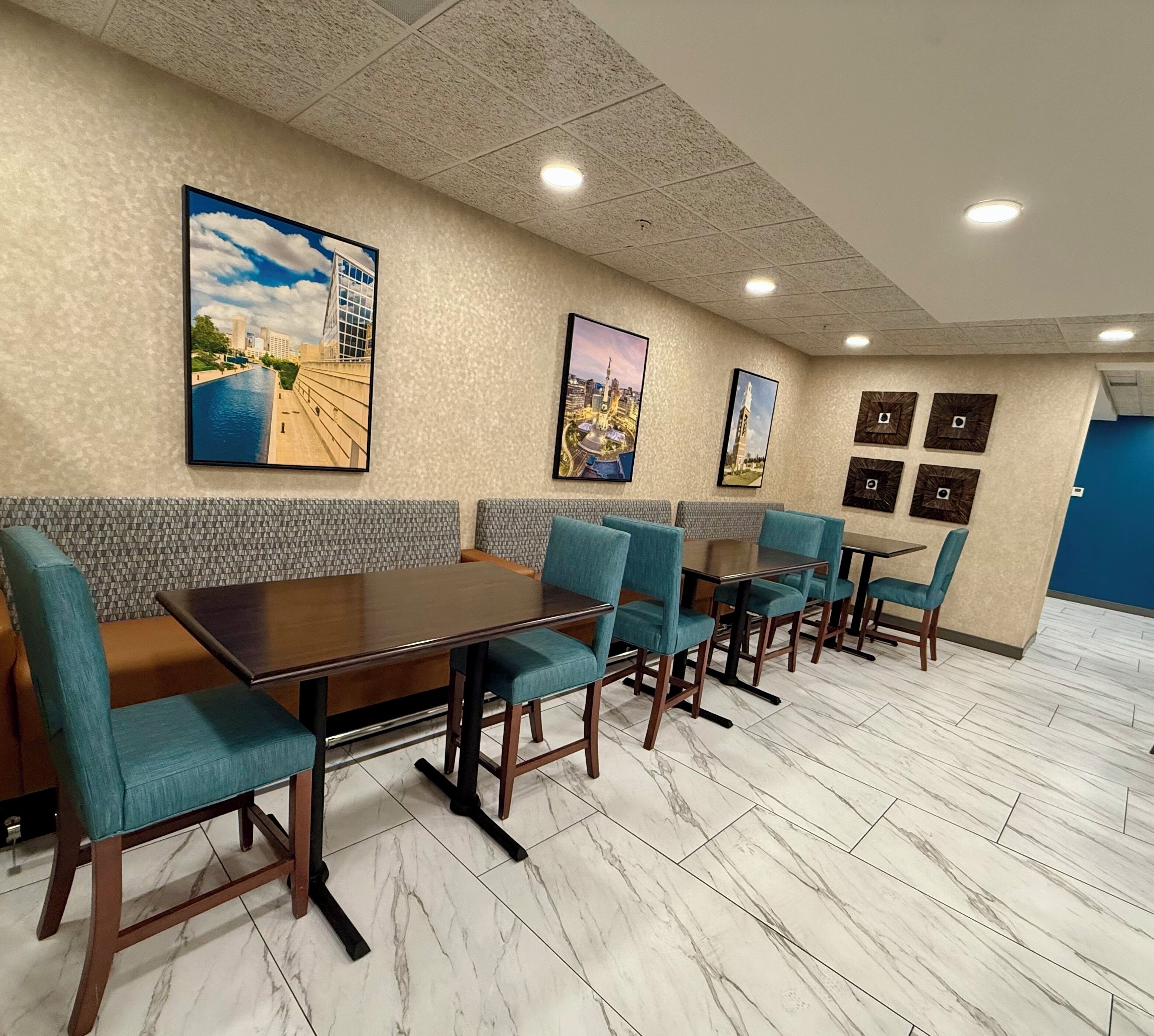 A dining area with a long table, blue upholstered chairs, and cityscape artwork on the walls.