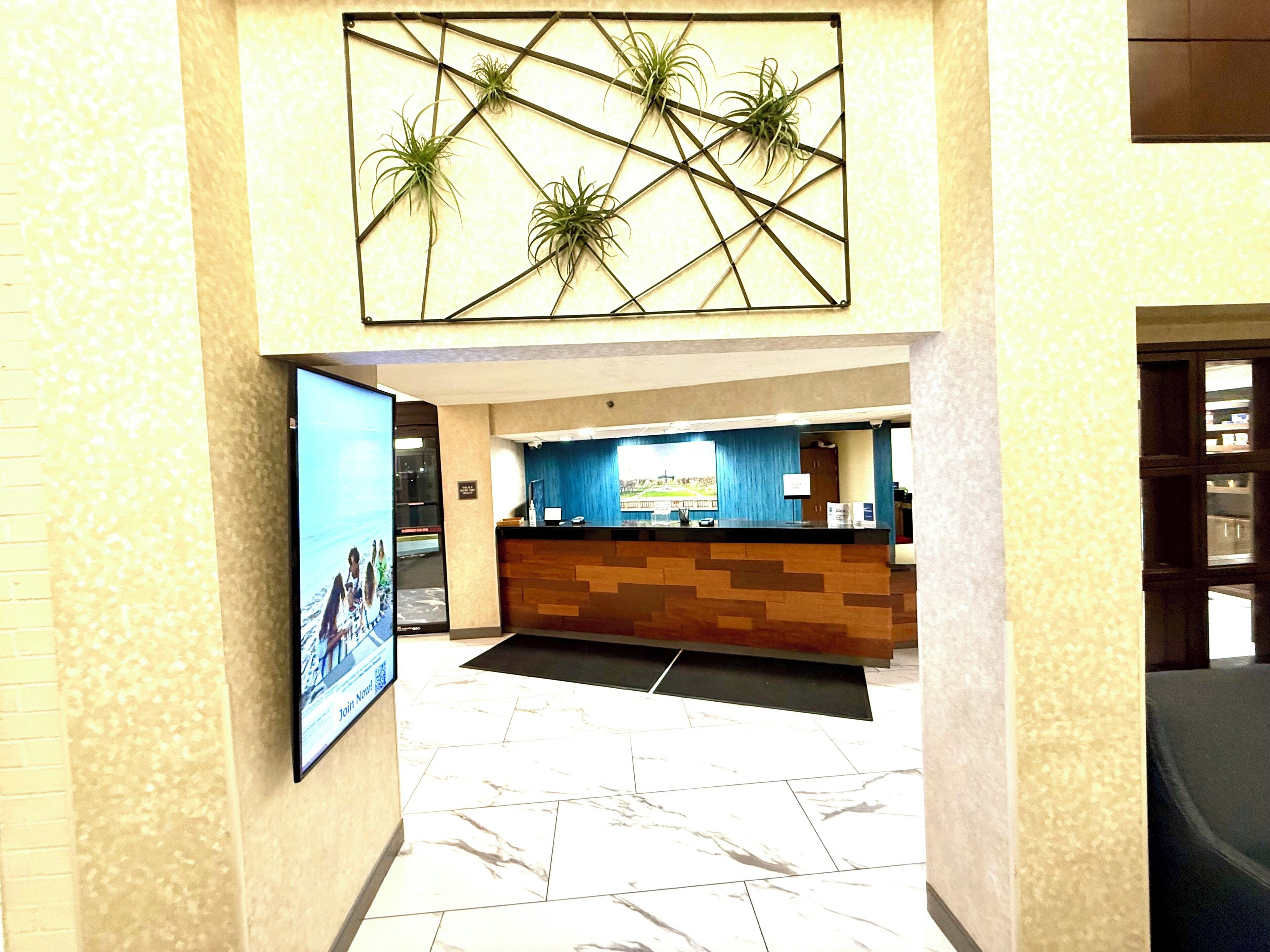 A reception area with a marble floor, a reception desk, and a wall-mounted plant display.