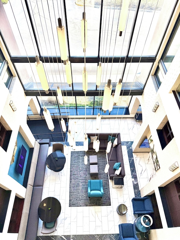 Um interior moderno com área de estar central, luminárias pendentes e grandes janelas.