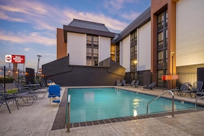 A hotel pool area with a modern building, lounge chairs, and a sign indicating the hotel is part of the Best Western Plus chain. - Best Western Plus Indianapolis North at Pyramids (Indianapolis)