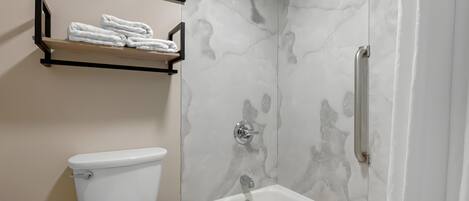 A bathroom with a toilet, a shower with a glass door, and a bathtub.