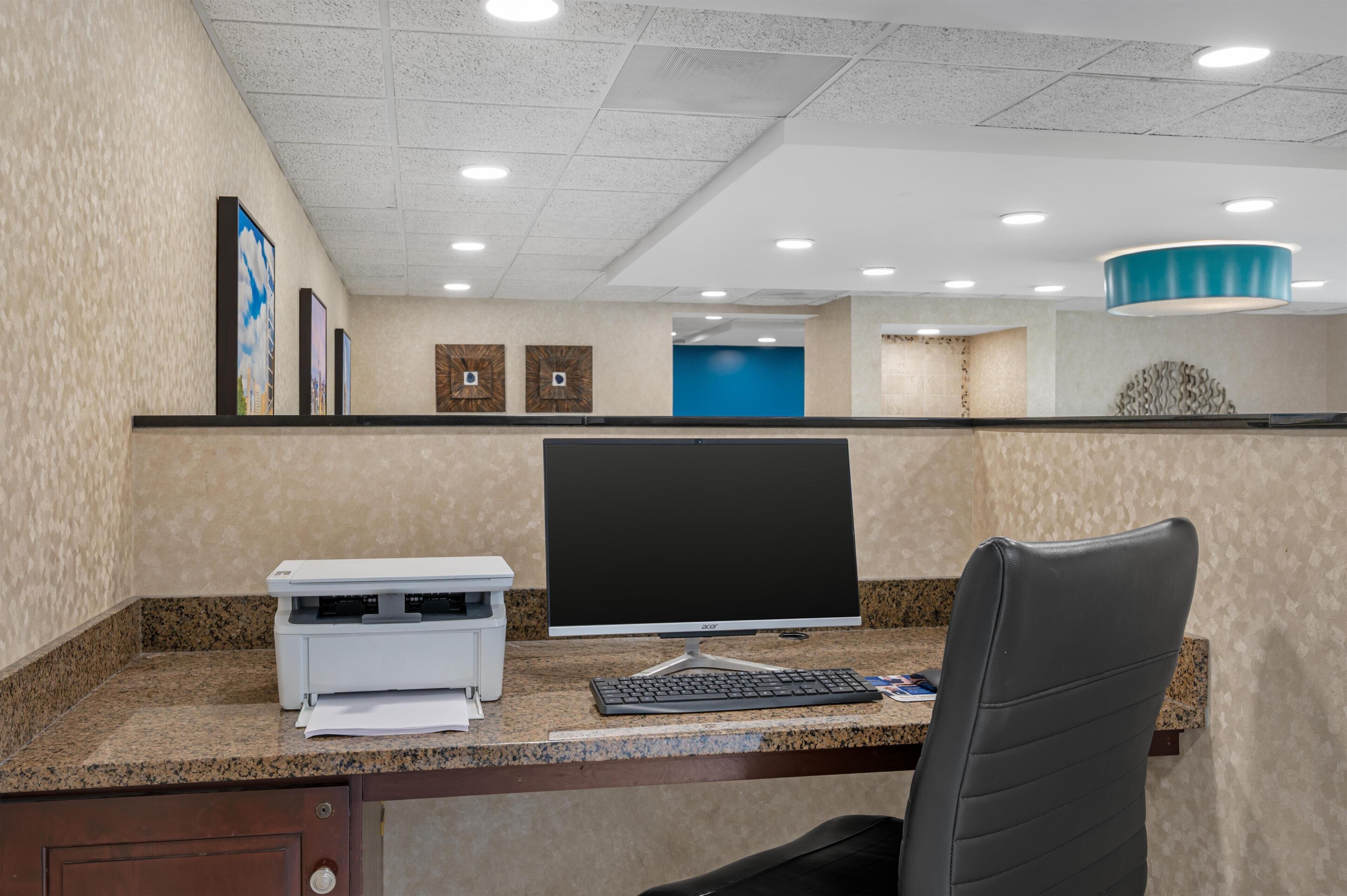 A reception desk with a computer, printer, and chair.